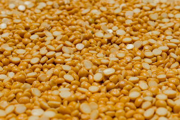 A close-up, full-frame view of vibrant yellow split peas (dal) filling the frame, showcasing a rich texture. This common food ingredient is popular in India.