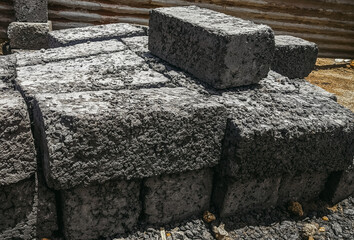 A close-up shot captures rough-textured concrete blocks stacked outdoors, ready for construction in...