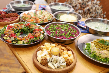 Olivier salad, sandwiches, canapés, bruschetta. A Christmas scene with meat delicacies against a dark wood background. An assortment of cheese and meat appetizers.