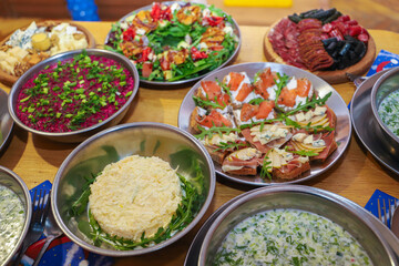 Olivier salad, sandwiches, canapés, bruschetta. A Christmas scene with meat delicacies against a dark wood background. An assortment of cheese and meat appetizers.