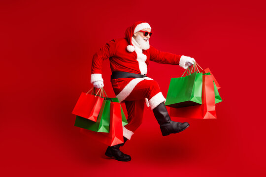 Santa in a red suit jumps with shopping bags against a bold red background celebrating Christmas spirit and holiday shopping