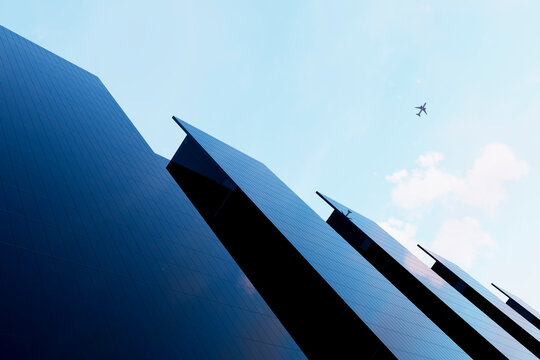 Airplane above 3D corporate towers in clear sky