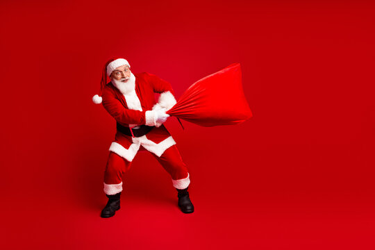 Santa battles a giant red sack in a playful Christmas themed image perfect for festive marketing and holiday stock photography