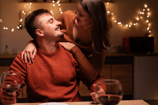 young smiling man and woman hugging has romantic dinner at home. Happy couple in love. Valentines day - Powered by Adobe