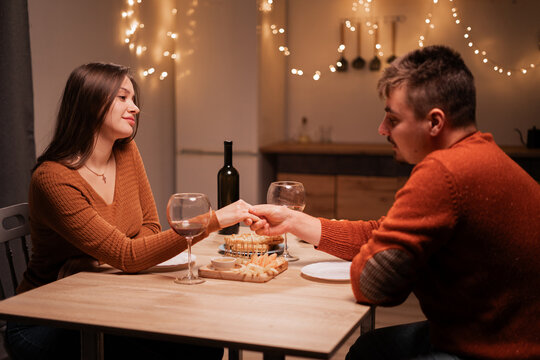 Happy young couple during their date at home, man holding his girlfriend's hand