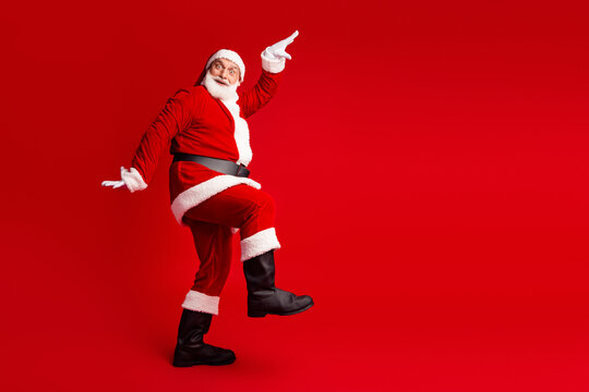 Santa in red costume kicks joyfully against a bright red background creating a festive christmas mood for stock images