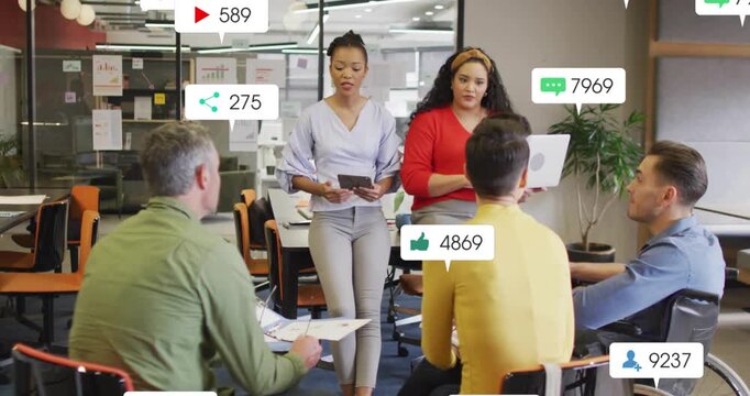 Main presenter using tablet and colleague laptop in business, 3rd icons appearing, covering faces