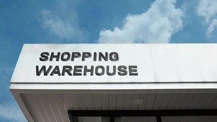 Shopping Warehouse word sign displayed on a large commercial retail building under a clear blue sky, symbolizing bulk retail, discount shopping, consumer goods, large format store, storage