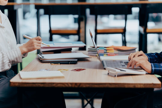 Modern Business Collaboration: Captured in a sleek, contemporary office space, two individuals are deeply engaged in collaborative work around a desk.