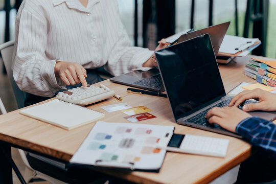 Collaboration and Calculation: In a modern workspace, hands are actively involved in both calculating figures and navigating digital interfaces.