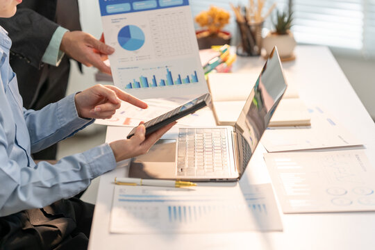 Analyzing the Data: Business Professionals reviewing statistical charts and laptop. Focused on business and professional office setting