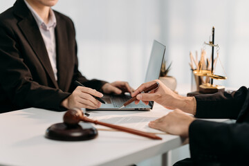 Legal Deliberation: Lawyers engage in a meticulous discussion, reviewing documents with a laptop and gavel symbolizing justice and law.
