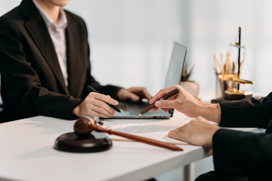 Legal Agreement: Two figures collaborate over contract document, a gavel in the foreground symbolizes legal action, while a laptop rests nearby symbolizing modern communication.