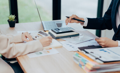 Workplace Collaboration: Two professionals engaged in a focused business meeting. They are seen engrossed in reviewing financial data, working diligently to achieve a successful outcome.