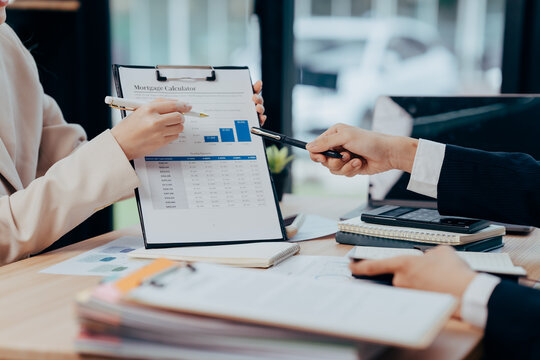 Financial Analysis in Conference: Two professionals collaborate, reviewing charts and reports with focused expressions.