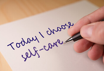 Obraz premium Hand writing a positive message Today I choose self care on a white piece of paper, emphasizing personal wellbeing, health, and a mindful approach to life