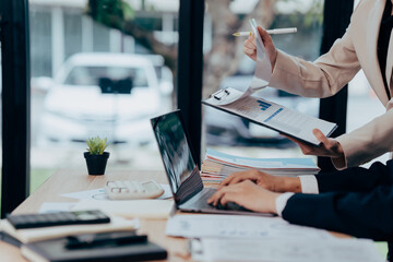 Collaborative Analytics in Modern Office: Two professionals diligently analyze data and strategies within a modern office setting. The image evokes a sense of efficiency and collaborative teamwork.