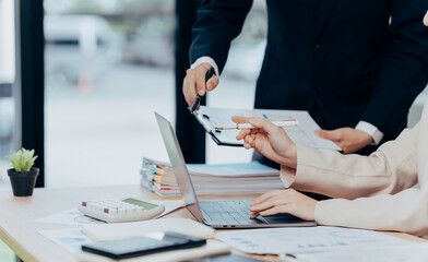 Team Collaboration in Office: Two professionals collaborate, examining documents and utilizing technology. An environment of efficiency, dedication and strategic planning emerges.