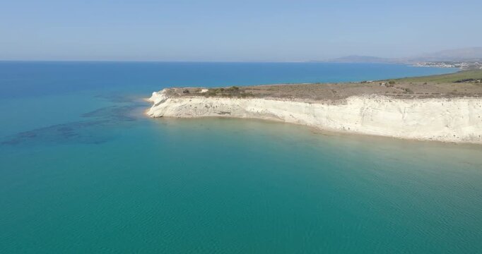 Aerial view of a promontory overlooking the azure and turquoise sea. It is Eraclea Minoa coastline, located in province of Agrigento, Sicily, Italy.