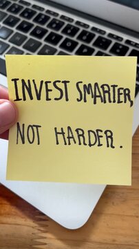 Motivational Quote: INVEST SMARTER, NOT HARDER Handwritten on Sticky Note over Laptop Keyboard
