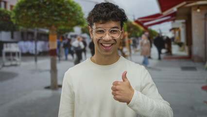 Young hispanic man wearing round glasses points finger to left on bustling downtown street;...