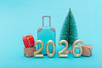 Toy suitcase and Christmas tree with golden 2026 numbers. Celebration of travel dreams and joyful holiday expectation.