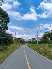 Rural Asphalt Road with Utility Poles Under a Blue Sky