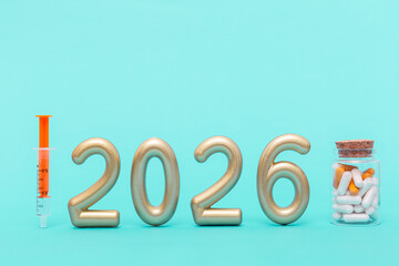 Golden numbers 2026 with syringe and bottle of pills. Symbol of healthcare progress, medical innovation and future treatment development.