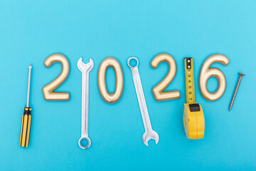 Golden numbers 2026 with metal tools on blue background. Concept of construction, repair, progress and building the future with precision and craftsmanship.