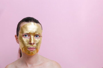 A woman with a golden facial mask against a pink background. The image represents self‑care, beauty and personal wellness. Copy space