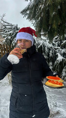 A young woman drinks champagne with a red caviar sandwich in her hands. 2026 against the backdrop of a New Year's tree.