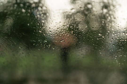 Raindrops, window, glass, wet surface with blurred green background and copy space, rainy day