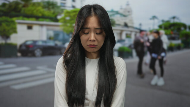 Young chinese woman outdoors on a bustling street with blurred pedestrians and greenery, wearing a white shirt, showing different facial expressions against an urban backdrop. - Powered by Adobe