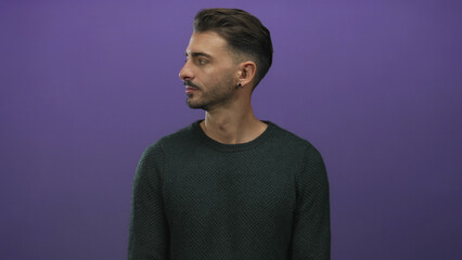 Man glances sideways with a smile and ear visible in a dark sweater in a studio portrait; curiosity intrigue wonder questioning.