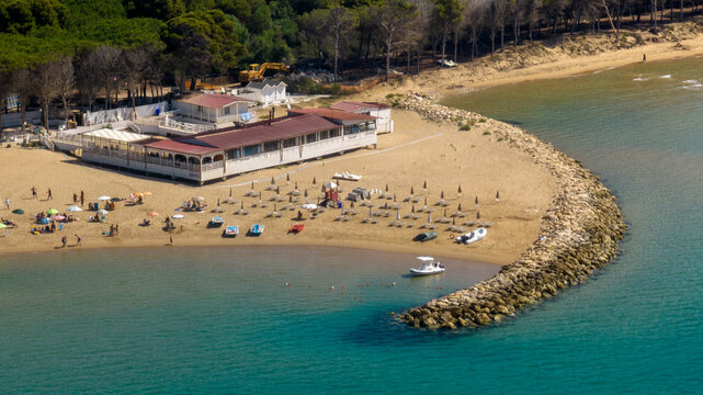 Aerial view from the sea of ​​a small sandy beach protected by breakwaters.