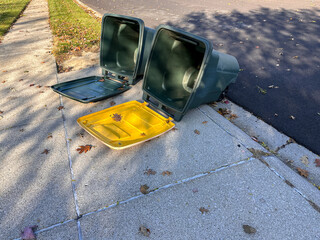 Empty trash cans blown over at the end of a driveway during a windy autumn day 
