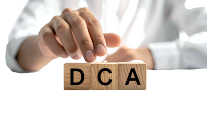 A person's hand placing a block labeled "A" beside "DCA" on three wooden blocks