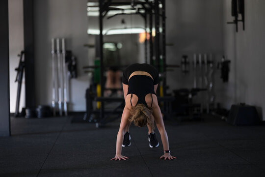Woman performs a handstand in a gym during a workout session focusing on strength and agility training - Powered by Adobe