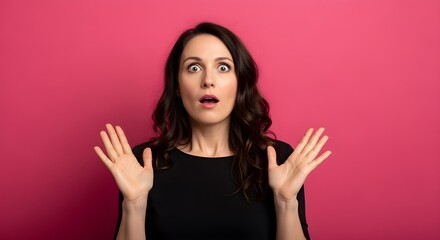 Astonished young woman with wide eyes and open mouth reacting with a look of surprise and disbelief against a vibrant pink background