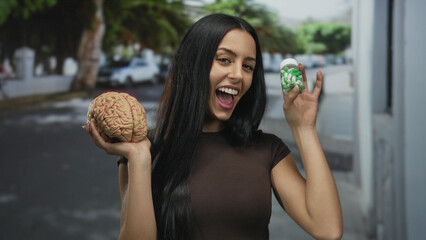 Woman smiling happily on a city street holding a model brain and bottle of pills, showcasing a...
