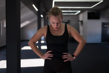 Woman taking a break after an intense workout in a modern fitness studio showing determination and...