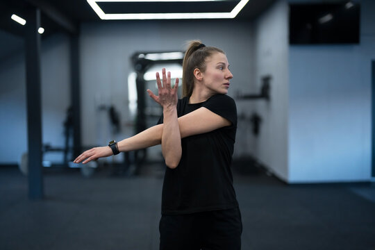 Woman stretching her arms before a workout in a modern gym setting during early morning hours
