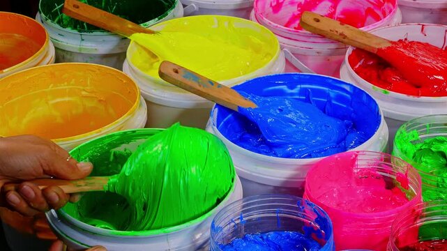 Scoop of Green Plastisol Ink from a White Bottle for Fabric Prints and more, showcasing thick textured paint and wooden spatulas. The image captures creativity artistic expression