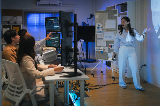 young Asian software development manager leads a late-night office discussion with his executive team, mentoring developers and analyzing source code to guide programming and project development	