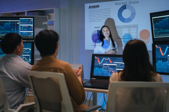 young Asian software development manager leads a late-night office discussion with his executive team, mentoring developers and analyzing source code to guide programming and project development