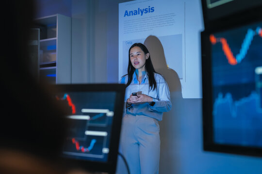 young Asian software development manager leads a late-night office discussion with his executive team, mentoring developers and analyzing source code to guide programming and project development	