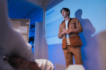 young Asian software development manager leads a late-night office discussion with his executive team, mentoring developers and analyzing source code to guide programming and project development	