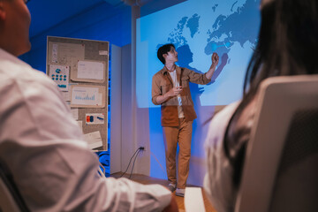 young Asian software development manager leads a late-night office discussion with his executive team, mentoring developers and analyzing source code to guide programming and project development	
