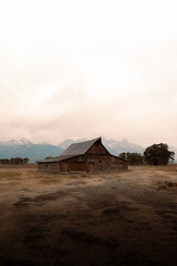 Rustic wooden barn on open field with distant mountains. © Sakan