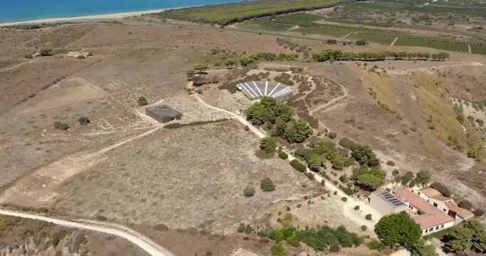 Aerial view of the theater of Eraclea Minoa. It's a ancient Greek theater located in the archaeological site of ​​Cattolica Eraclea, in province of Agrigento, Sicily, Italy. In background is azure sea